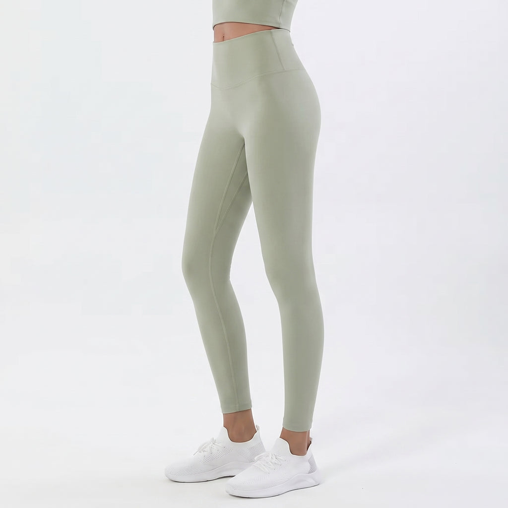 A model wearing sage green high-waisted leggings and white sneakers, shown from the waist down against a clean white studio background.