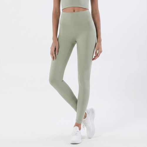A model wearing high-waisted sage green leggings and white sneakers, shown from the waist down against a clean white studio background.